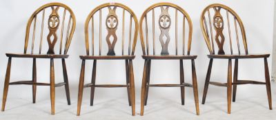 A set of 4 20th century Ercol beech and elm wood ' fleur de lys ' dining chairs being raised on