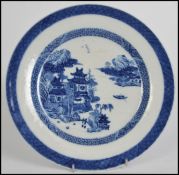 An 18th / 19th century Chinese blue and white ceramic plate in the willow pattern with scenes of