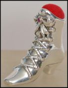 A silver Victorian style ladies boot pin cushion being inset with rubies and having a red baize