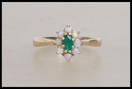 A hallmarked 9ct gold ring set with  a central green stone surrounded by an opal halo. Hallmarked