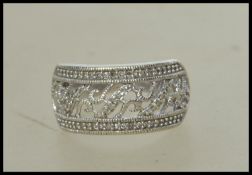 A 10ct white gold and diamond band ring with channel set diamonds in a pierced and scrolled