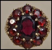 A hallmarked 9ct gold and garnet 1970s cluster ring having pierced and textured gallery and