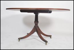 A Regency style walnut and mahogany oval breakfast / loo tilt top dining table. The crossbanded oval