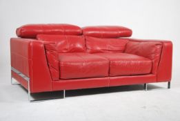 A contemporary red leather Italian sofa raised on