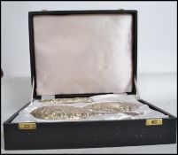 A vintage silver hallmarked vanity set consisting of mirror and brushes having a rococo leaf and