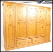 A large antique style pine 5 door wardrobe compactum being raised on plinth base with deep drawers