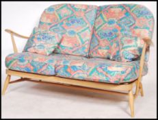 An Ercol beech and elm wood Windsor pattern two seat sofa settee raised on turned legs with