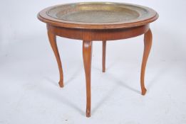 A mid century oak and brass Indian tray top table. The unusual tray handbeaten in relief with