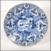 An 18th century delft charger in blue and white having central pagoda and lake with fisherman