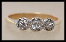 An early 20th century 18ct gold three stone diamond ring set with three old cut diamonds in an
