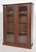A 1930s mahogany twin door china display cabinet with shelves raised on a veneered plinth base.