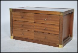 A 1970's teak and glass campaign style coffee table having inset smoked glass table top being raised