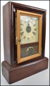 An early 20th century American gingerbread clock set in a rosewood case having a Roman numeral