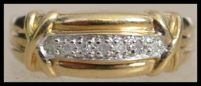 A hallmarked 9ct gold and diamond band ring with 7 illusion set diamonds and kiss cross shoulders.