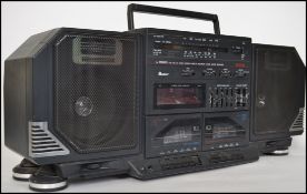 A vintage 1980s oversized Academy ghetto blaster / boom box radio in black having a handle atop.