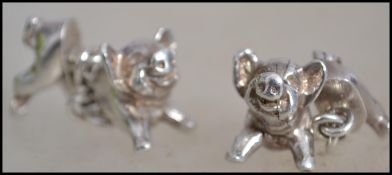 A pair of hallmarked silver cufflinks in the form of pigs the head and rear of the pig being
