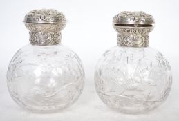 A pair of stunning silver topped hallmarked perfume bottles, the silver hinged lids decorated in