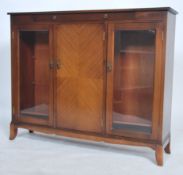 A mid century Regency revival bookcase cabinet being raised on squared legs having glass door