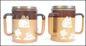 Two Royal Doulton stone wear salt glazed three handled harvest loving cups with hallmarked silver