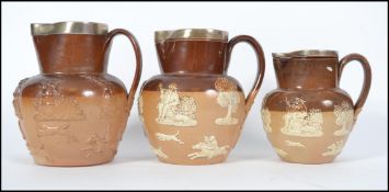 A group of three Doulton Lambeth stone wear salt glazed graduating harvest jugs with silver rims
