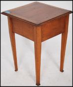 An early 20th century golden oak pedestal sewing box being raised on square tapered legs with flared