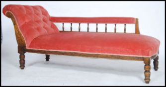 An Edwardian oak chaise longue day bed having turned legs with vibrant pink upholstered fabric