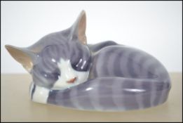 A Royal Copenhagen ceramic sleeping cat figurine 057 along with a Royal Doulton Images Of Nature cat