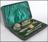 A silver hallmarked vanity set consisting of scissors, file, lidded pot, tooth brush etc. held