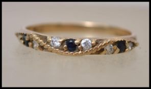 A hallmarked 9ct gold half eternity ring set with blue sapphires and white stones with rope style