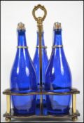 A vintage 20th century blue glass decanter set complete in a two tier ebonised holder with gilt