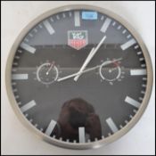 A reproduction Tag Heuer wall clock with black dial and baton numerals having central Tag motif