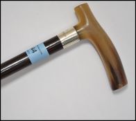 A silver collared horn handled ebonised promenade cane having inscription to the silver band reading