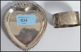 A hallmarked silver pin dish / peanut dish in the form of a heart having beveled edges and floral