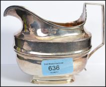 An early 19th century silver hallmarked creamer jug having a geometric shaped handle bearing