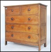 An early 20th century Arts & Crafts Cotswold type solid oak chest of drawers being raised on squared