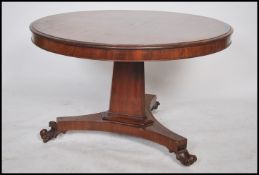 A Victorian mahogany tilt top circular breakfast / loo dining table being raised on a tripod base