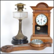 A late 19th century oil lamp together with an eight day wooden cased mantle clock and a 20th century