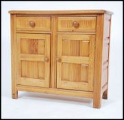 An Ercol style pine dresser base having chamfered edge top over twin drawers and cupboards