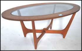 A 1970's teak and glass Danish influence oval coffee table in the atomic style with shaped legs