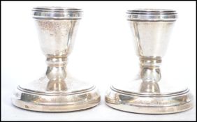 A pair of hallmarked silver candlesticks of squat form being hallmarked for Birmingham 1989.