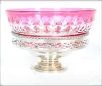 A silver hallmarked tazza bowl with pierced galllery sides having an inset cranberry flash glass bon