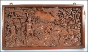 An unusual Thai carved hardwood panel in relief depicting scene of workmen in a forest with trees