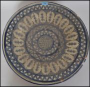 A large delft ceramic wall charger bowl in blue and white decorated with geometric patterns.