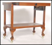 A vintage mid 20th century two tiered metamorphic drinks trolley converting to a serving table