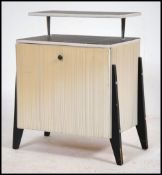 A 1950's retro two tone upholstered bedside cabinet being raised on ebonised supports with gallery