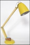 A retro mid century Terence Conran Mac Lamp in yellow having bell shaped shade and terraced base