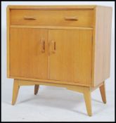 A 1950's sideboard cabinet by Ernest Gomme / G-Plan oak comprising of a short drawer over twin