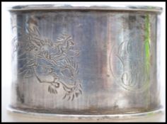A Chinese silver hallmarked napkin ring decorated with a dragon being hallmarked to the inside