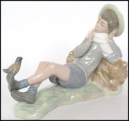 A Lladro figurine of a boy with bird on foot resti