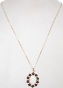A 9ct gold and and red stone pendant and necklace combination. The oval cut opal surrounded by
